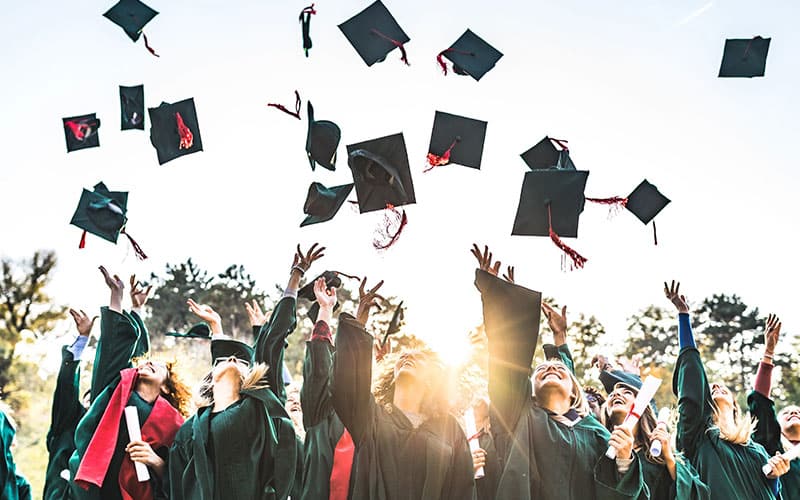 Students toss their hats in the air during a graduation ceremony.
